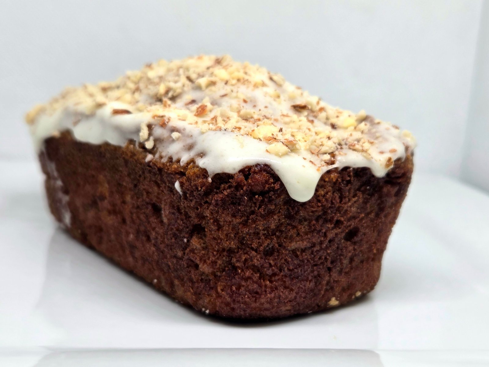 Spiced bread loaf topped with vanilla glaze and chopped nuts