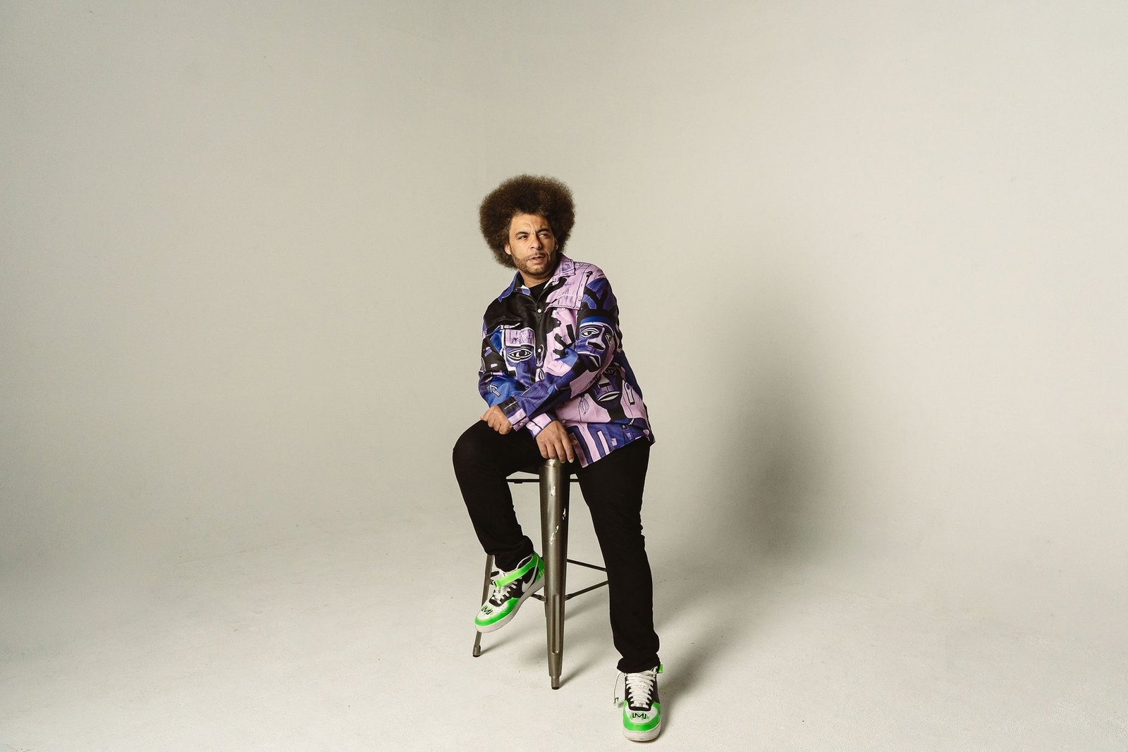 Little Moses Jones, founder of Urban Bread Co, seated on a stool in a patterned purple shirt