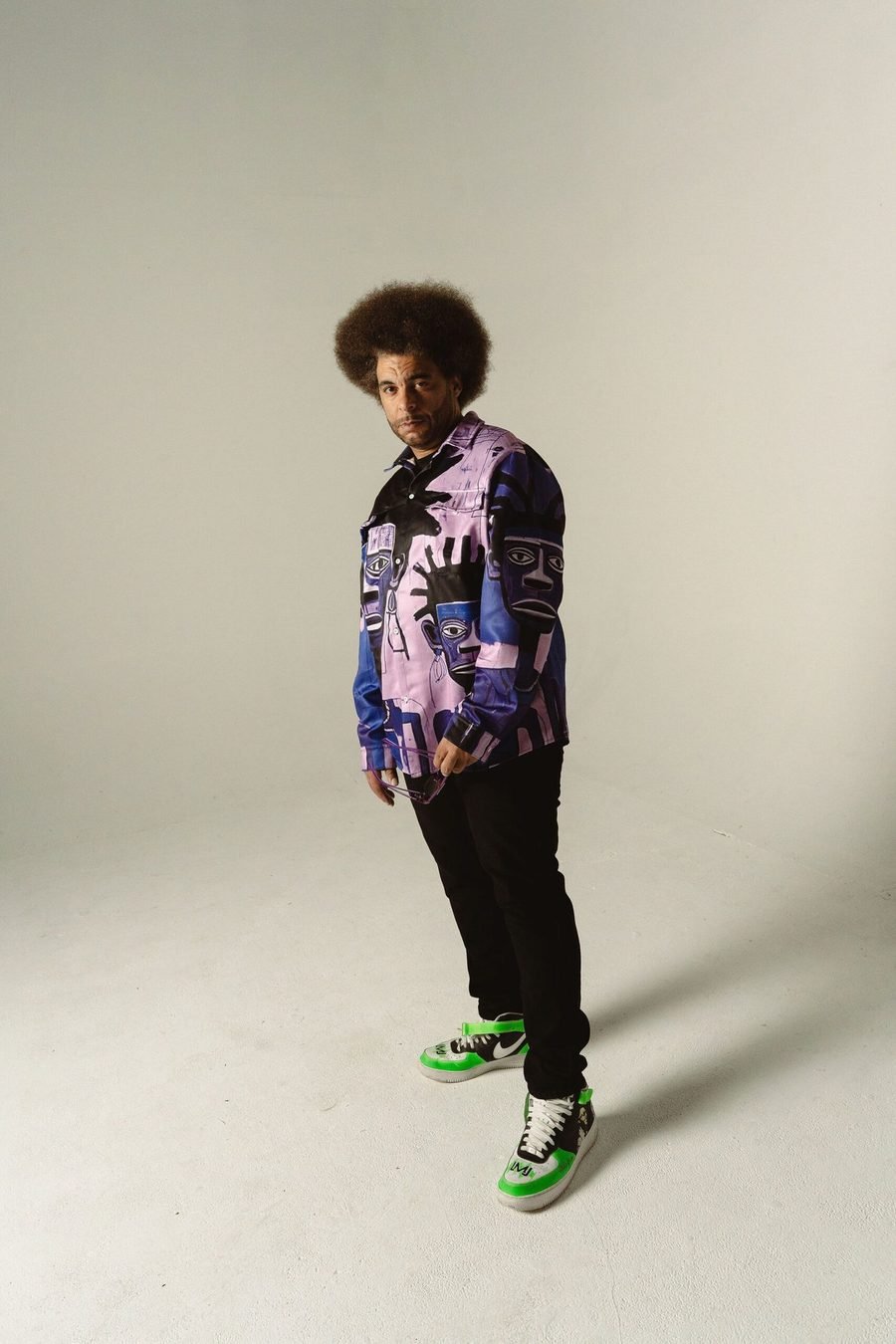 Little Moses Jones standing in a patterned purple shirt and green sneakers